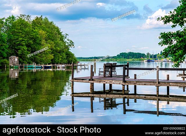 A jetty with two chairs at the shore of the Steinhuder Meer with a view at the bathing island in Steinhude, Lower Saxony, Germany