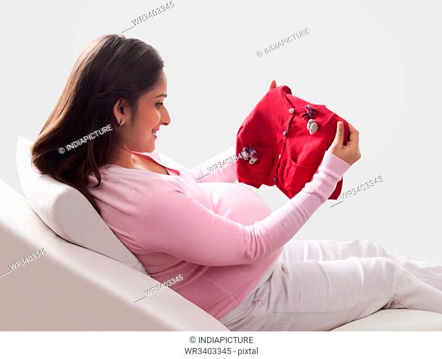 Pregnant woman holding baby clothing