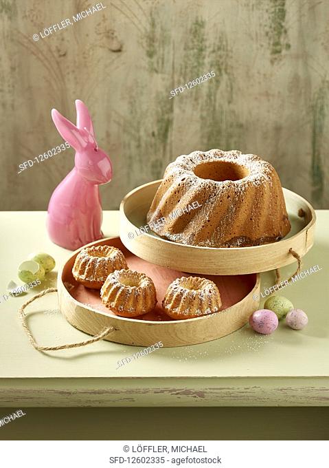 A Bundt cake and mini Bundt cakes dusted with icing sugar with Easter decorations