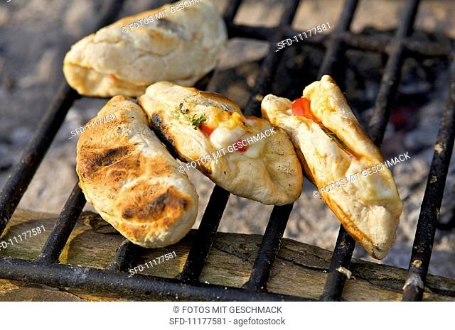 Small calzones on a grill rack over an open fire