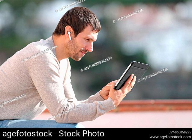 Serious man watching media with tablet and earbuds