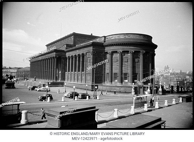 A view of the north and east front of St George's Hall, seen from the north, with a statue on the steps to the hall, an equestrian statue to the east of the...