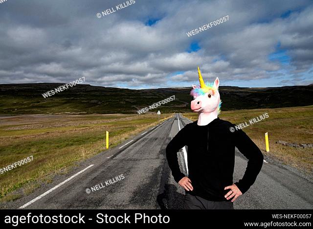 Man wearing unicorn face mask standing on highway