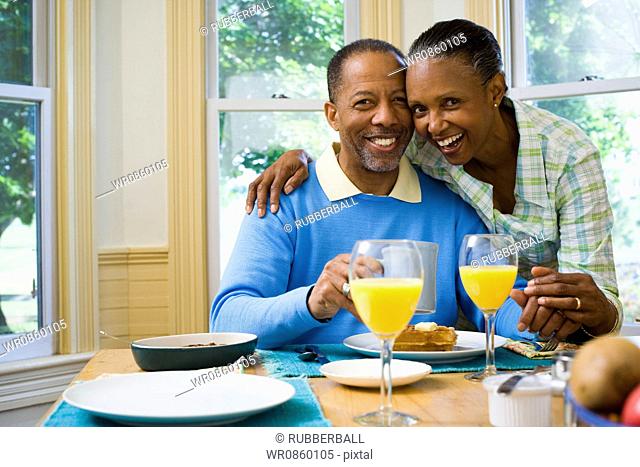 Senior man and a senior woman smiling at the breakfast table