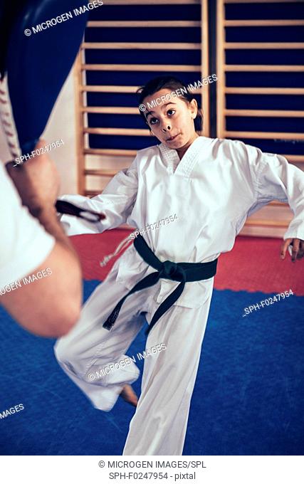 Girl in taekwondo class with trainer