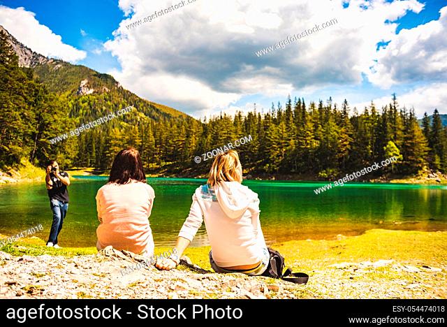 Gruner See, Austria 16.05.2017: Peaceful mountain view with famous green lake in Styria. Turquoise green color of water. Tourists sitting on the shore