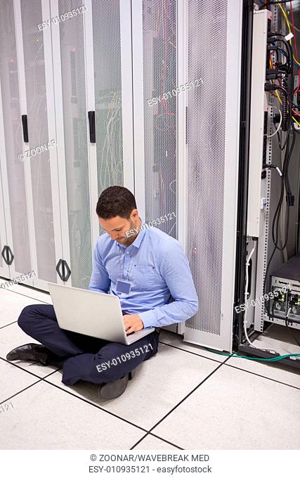 Technician looking at his laptop while doing maintenance on servers