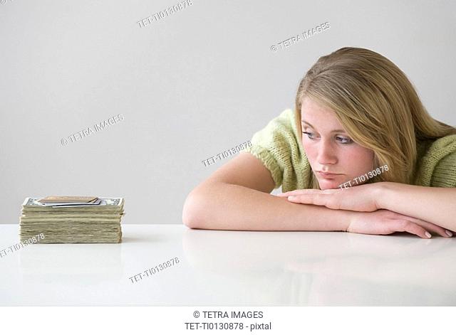 Teenaged girl looking at stack of money