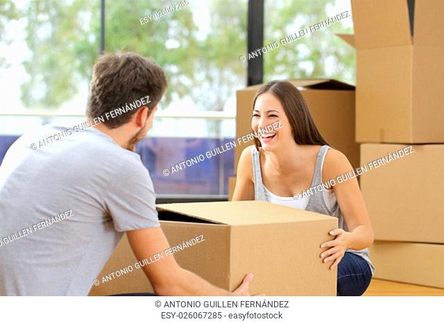 Happy couple or marriage lifting boxes moving home