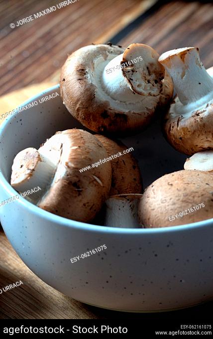 White bowl with portobello mushrooms on wooden board