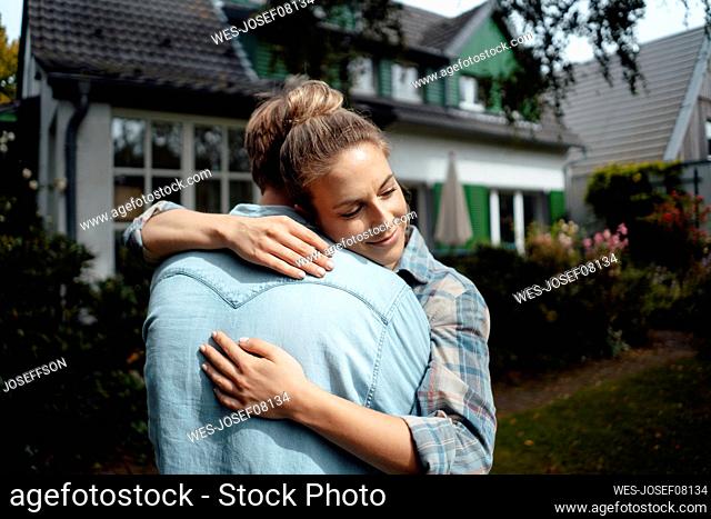Smiling woman hugging boyfriend at backyard