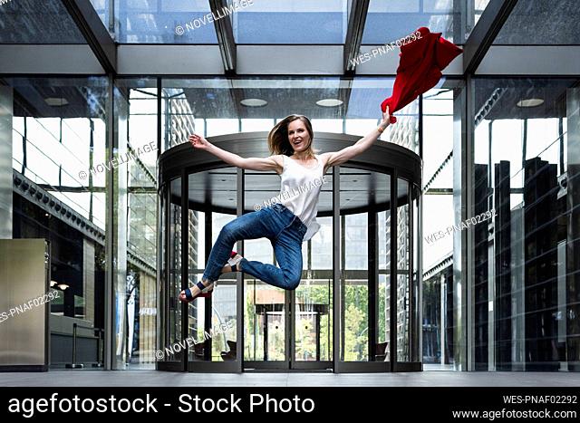 Happy businesswoman with blazer jumping at entrance