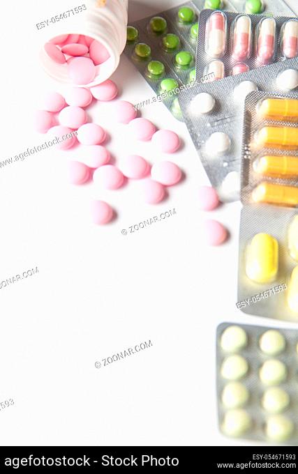 Packages of colorful tablets with bottle of pink scattered pills
