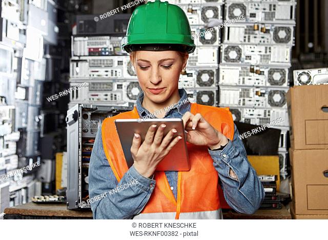 Female worker in computer recycling plant using digital tablet