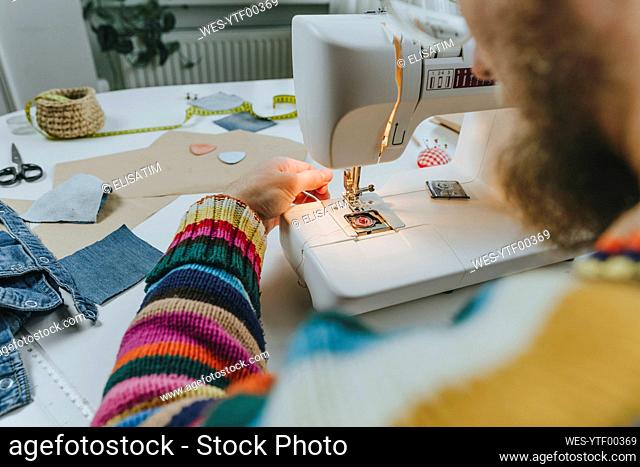 Fashion designer adjusting thread in sewing machine