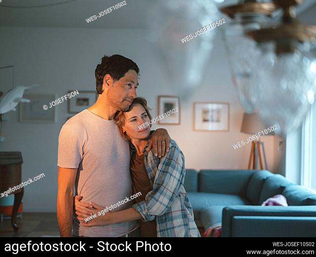 Smiling mature woman hugging man standing in living room at home