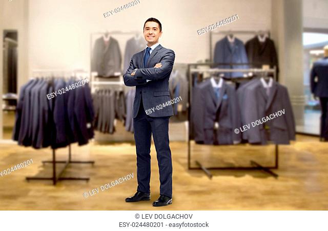 business, people, menswear, sale and clothes concept - happy smiling businessman in suit over clothing store background