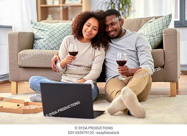 happy couple with laptop drinking red wine at home