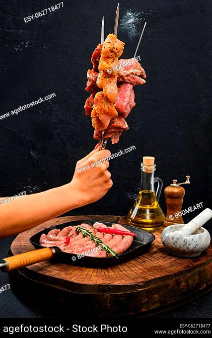 Hand holds skewers with marinated meat