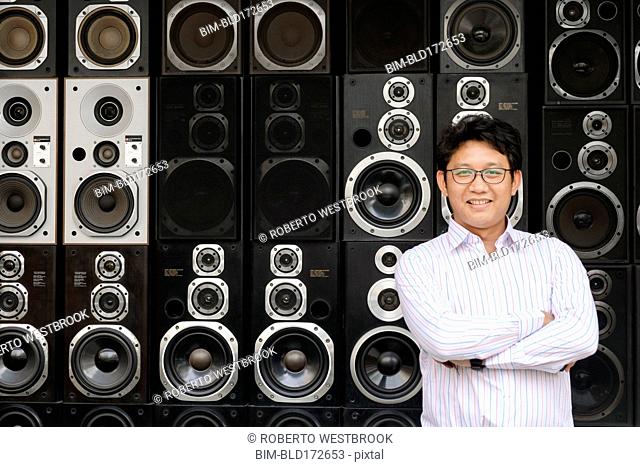 Asian man standing by stacked speakers