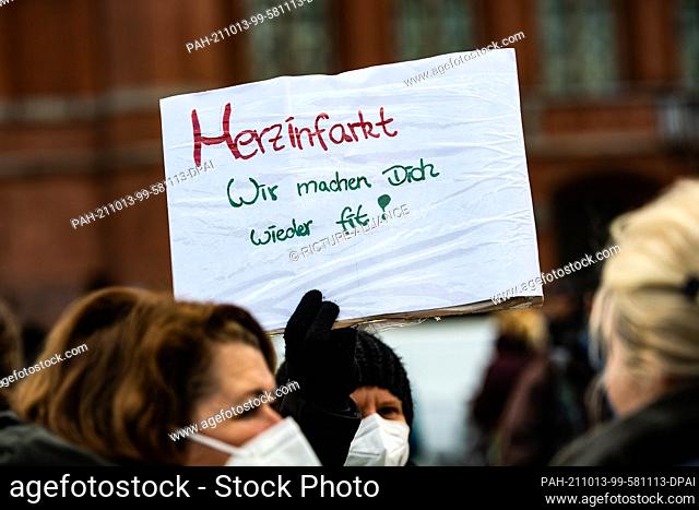 13 October 2021, Berlin: A Vivantes nurse holds a sign with the slogan ""Heart attack - We'll get you fit again!"" during a demonstration by Vivantes and its...