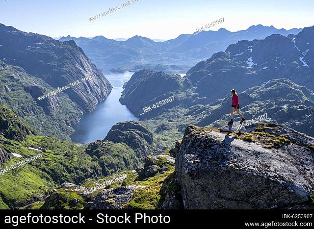 Hiker, young woman in the mountains, hiking to Trollfjord Hytta, fjord with mountains, hiking to Trollfjord Hytta, at Trollfjord and Raftsund, Lofoten, Nordland