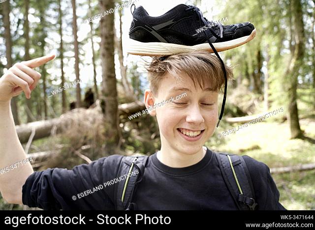 Young boy in forest with sneaker on his head. Bad Tölz, Upper bavaria, Germany