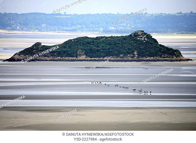 hikers crossing bay of Mont Saint-Michel at low tide, Tombelaine islet in the background, view from Mont Saint-Michel monastery, Normandy, France