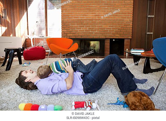 Father playing with son in living room