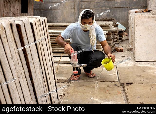 A HARD WORKING LABOURER USING ELECTRIC EQUIPMENT ON TILES