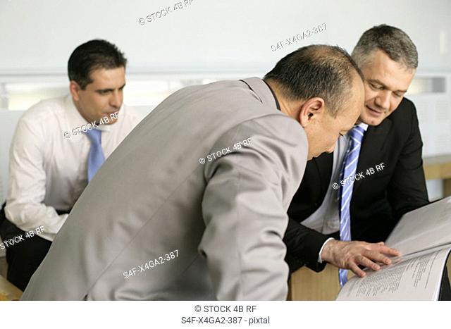 Three businessmen looking at a folder with documents