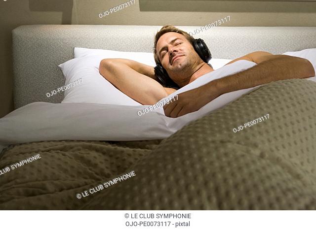 Man sleeping in bed with headphones