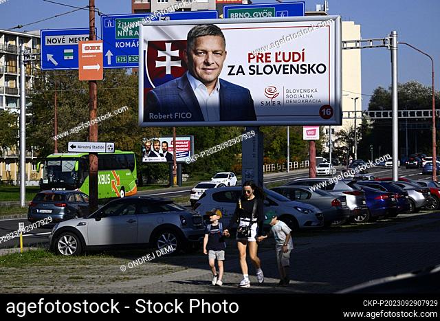 A woman with children walks past an election poster of Robert Fico, former prime minister and leader of the political party Smer-SD