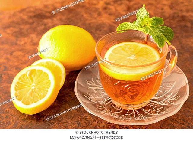 Lemon Tea - Cup of lemon slices with tea and mint leaf on a rustic wooden background. Close up, Selective Focus