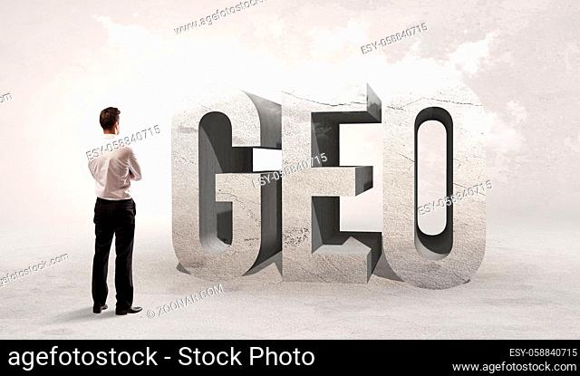 Rear view of a businessman standing in front of GEO abbreviation, attention making concept