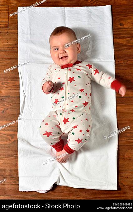 high angle view of a baby on the parquet floor in pajamas, smiling