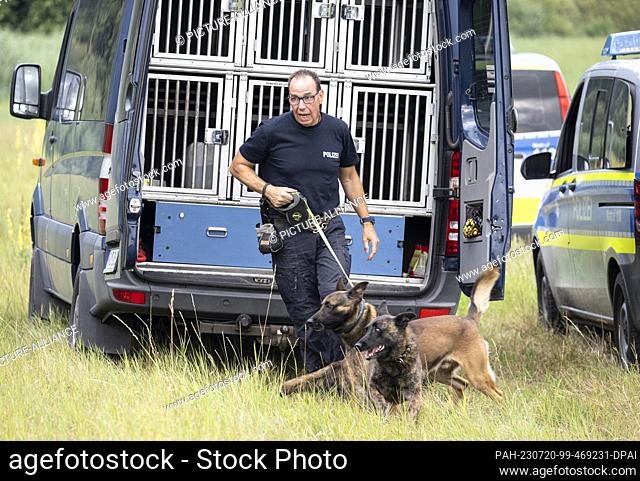 20 July 2023, Hesse, Villmar: Police officers are using sniffer dogs to search for the body of a woman on the banks of the Lahn River