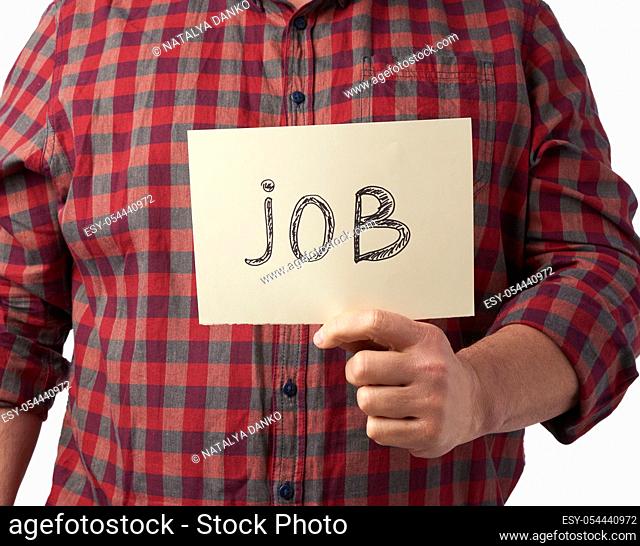 man in a plaid shirt and jeans holds a piece of paper with the inscription job, unemployment concept against the backdrop of the global crisis, fired employee