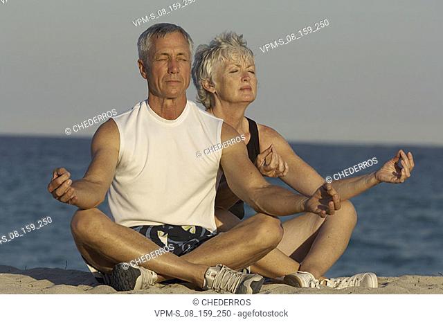 Senior couple meditating on the beach