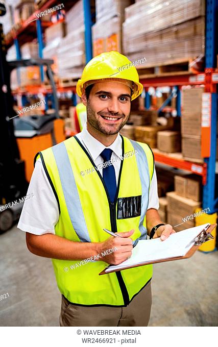Smiling warehouse manager with clipboard