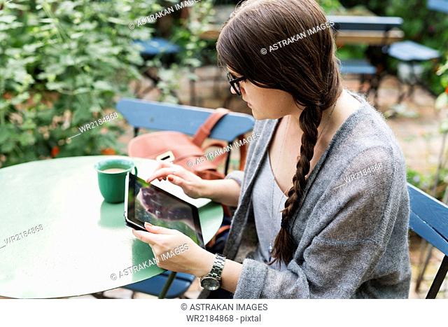 High angle view of woman working on tablet in coffee break at greenhouse