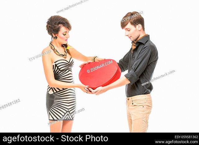 beautiful young couple looking like dolls. woman and man holding big red heart shape present box isolated on white background. Copy space