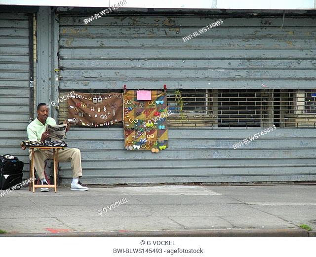 street hawker reading newspaper, USA, Manhattan, Harlem, New York