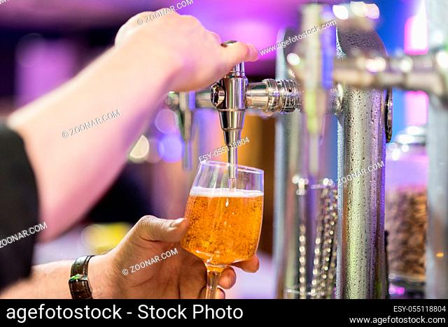 Bartender pouring lager beer in a glass. Shallow dof, selective focus