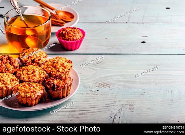 Healthy Dessert. Oatmeal muffins with cup of green tea over light wooden background. Copy Space