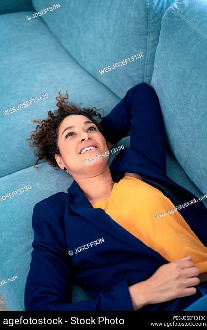 Thoughtful businesswoman relaxing on sofa at workplace