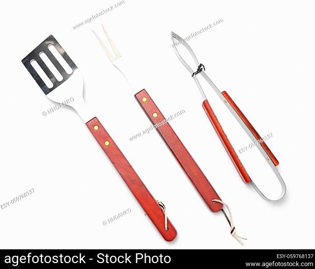 tongs, metal spatula and a fork with a wooden handle on a white background, picnic utensils