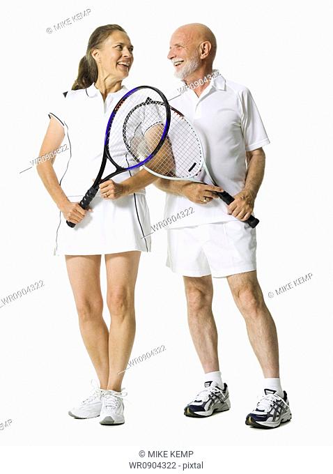 Senior couple standing with tennis rackets