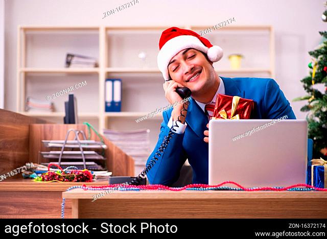 Young male employee celebrating Christmas in the office
