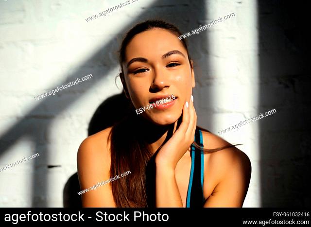 Portrait of beautiful woman. Close up face of sporty woman looking at camera on gray wall with copy space. Happy fit girl in sportswear laughing